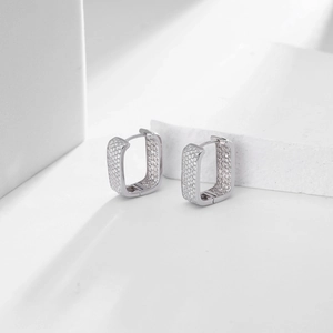 Detail of square silver hoop earrings with shimmering paved zircon stones and sleek metal finish