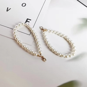 Detail view of two white faux pearl chains with elegant gold lobster clasps for accessories
