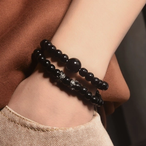 Set di bracciali da uomo in ossidiana con ciondoli a corona indossati con stile retrò