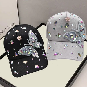 Detailed macro of crystal butterfly embroidery and pink flower decor on baseball caps