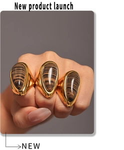 Close-up of three 18K gold-plated teardrop rings with natural brown wood grain stones