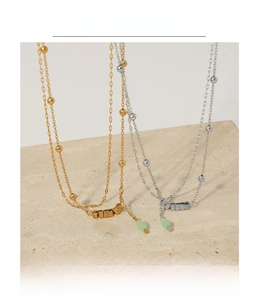Detail of double-layer stainless steel anklets with beads and green teardrop charms