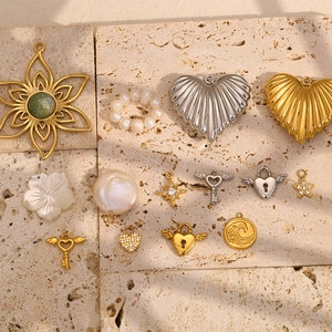 Collection of 18K gold plated heart and angel key pendants on a stone surface