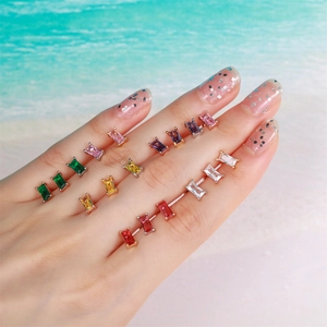 Fashion colorful zircon earrings in geometric flower shapes on a hand by the sea