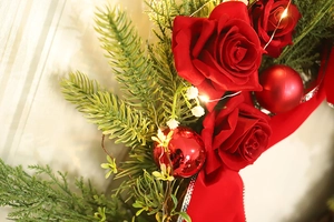 Detail of Christmas wreath with red roses, pine needles, and warm LED string lights