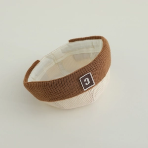 Detail of knit beanie featuring two-tone texture and leather patch with letter C