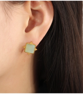 Detail view of square gold-plated earrings with natural green stone on a model