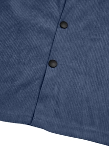 Macro shot of navy blue corduroy fabric showing ribbed texture and black snap buttons