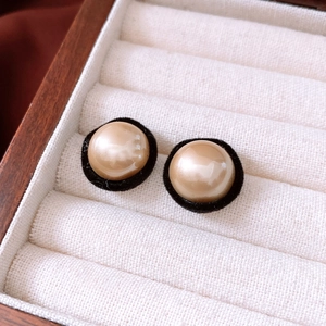 Macro shot of elegant champagne faux pearl earrings with black velvet circular trim