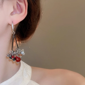 Détail de boucles d'oreilles à pompons vintage avec zircons et franges de perles colorées