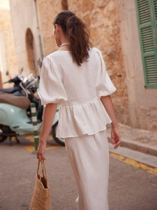 White cotton two-piece skirt set with puff sleeve blouse and maxi skirt on sunny street