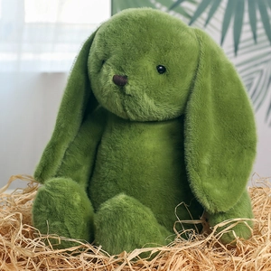 Detail of green plush bunny rabbit toy with soft long ears sitting in a straw nest