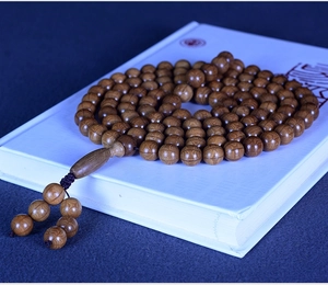 Detail of multi-layered wooden prayer beads with natural grain on a book