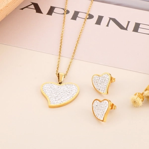 Macro shot of gold heart necklace and earrings set with sparkling diamond pave details