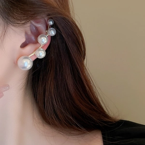 Detail of elegant gold ear cuff with five gradient white pearls on a model's ear
