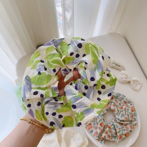 Detailed macro of two floral scrunchies with green leaf and blue flower patterns