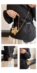 Détail d'un mini sac fleur dorée avec perle centrale blanche et fine chaîne à boules