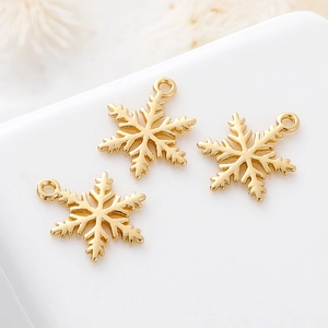 Detailed view of three gold snowflake charms for DIY jewelry making on white surface