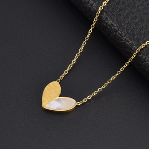 Golden heart necklace with white mother-of-pearl inlay on dark leather background