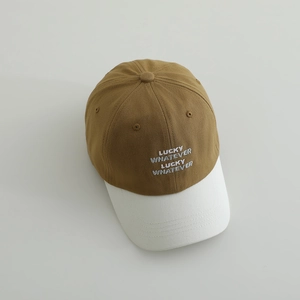 Macro view of Lucky Whatever embroidery on a brown and white cotton baseball cap