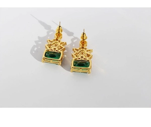 Detailed macro view of vintage gold earrings with emerald green stones and diamond accents