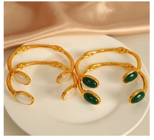 Detail of vintage 18k gold plated stainless steel bangles with white and green cat eye stones