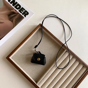 Detail view of mini black leather bag pendant with gold snap on wood jewelry tray