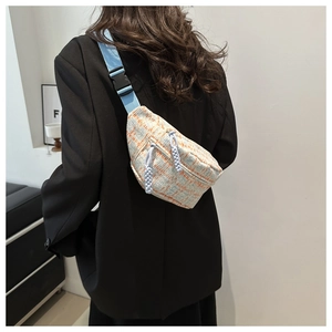Detailed view of light blue woven crossbody bag with adjustable strap and zip detail