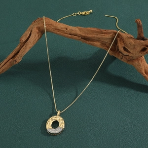 Macro view of gold donut pendant with pavé zircons hanging on vintage wood prop