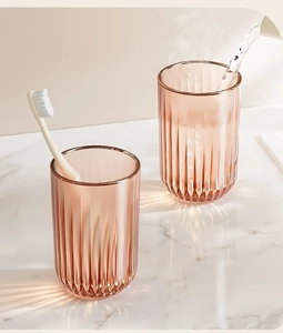 Detail of amber striped magnetic toothbrush cups on white marble countertop