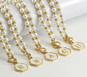 Détail de colliers en perles d'acier inoxydable avec pendentifs alphabet hexagonaux