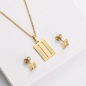 Detail of gold titanium steel jewelry set featuring Greek key motif on pendant and earrings