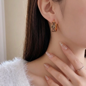 Vintage gold plated C-shaped hoop earrings with leopard print pattern on model