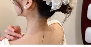 Detail eines weißen Organza-Blumenhaargummis mit geschichteter, transparenter Textur