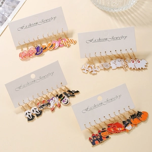 Detailed set of Halloween dangle earrings with colorful enamel charms on warm beige background