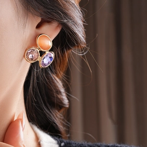 Close-up of vintage oval earrings with cat's eye stone and colorful crystals