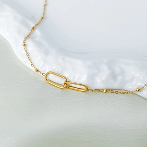 Detailed close-up of interlocking gold oval rings on a delicate satellite bead chain