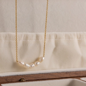 Detailed macro of 18K gold plated chain with five natural freshwater pearls in a jewelry box