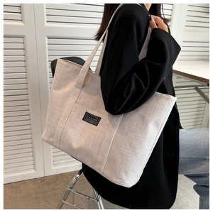 Detailed view of oatmeal canvas tote bag showing large capacity and FASHION embroidery