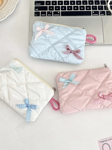 Set of three quilted bow cosmetic bags in blue, white, and pink with metal zippers