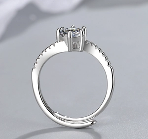 Detail of four-prong silver ring featuring a round solitaire and pavé stones