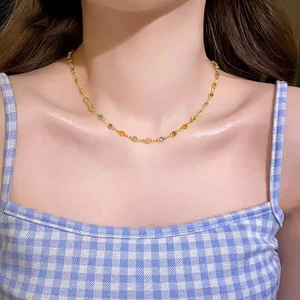Détail d'un collier chaîne en or avec des perles de pierres précieuses colorées sur le cou