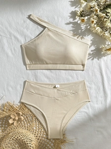 Chic beige one-shoulder ribbed bikini set with high-waisted bottoms on resort background