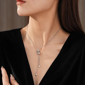 Detail of adjustable silver long necklace with heart pendant on model in velvet dress