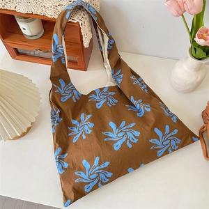 Detailed close-up of blue floral canvas tote bag with brown base and wide shoulder strap