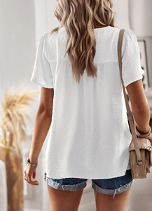 Detail of white short sleeve top with textured polka dot pattern and loose back fit