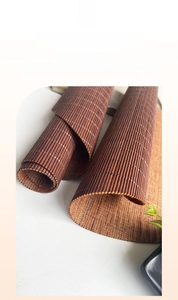 Detail of rollable dark brown bamboo tea mat with laser-engraved edges and woven texture