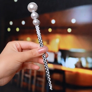 Detail of checkered hair pin with white pearls and black and white pattern design