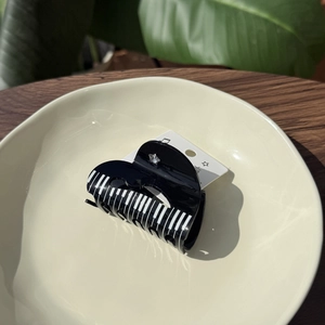 Detail of black piano key hair claw clip with star rhinestone in a ceramic dish