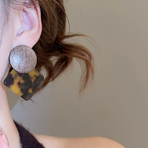 Detail of geometric leopard print earrings with metal stud and acetate pendant